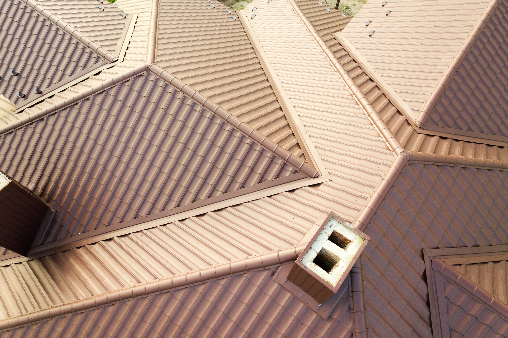 Detail of house roof structure covered with brown metal tile sheets