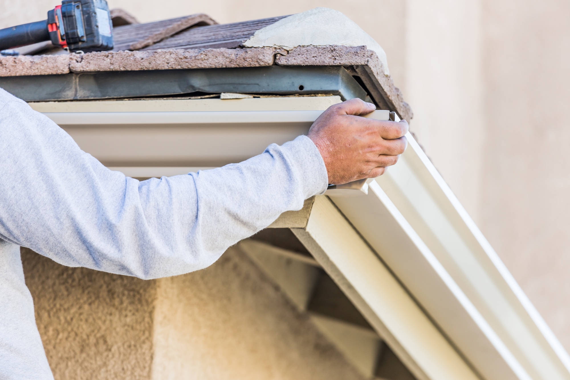 Worker Attaching Aluminum Rain Gutter to Fascia of House